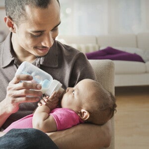 Baby girl drinking her bottle on daddy's lap