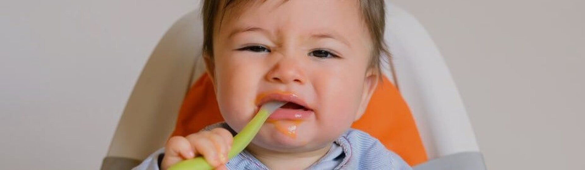 Baby with spoon in mouth looking unimpressed